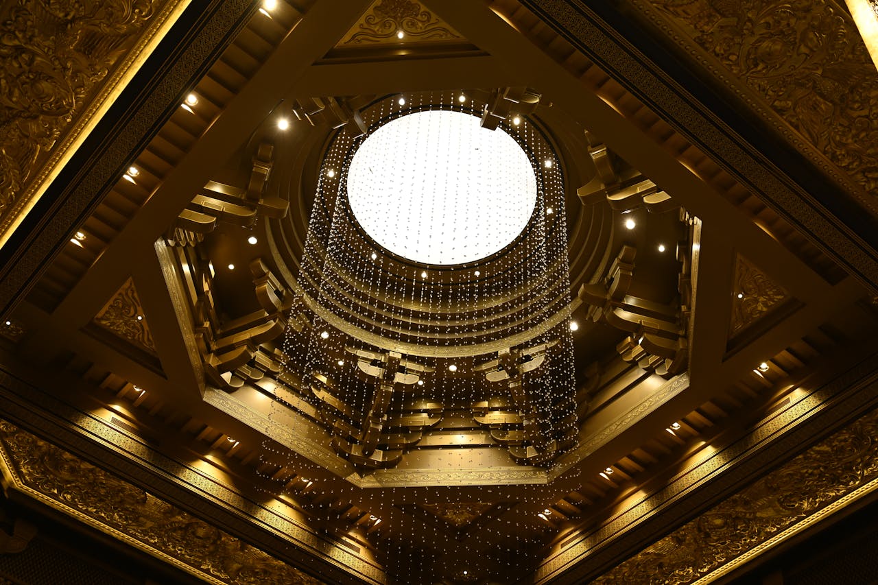 A stunning view of a lavish golden chandelier hanging from an intricately designed ornate ceiling.